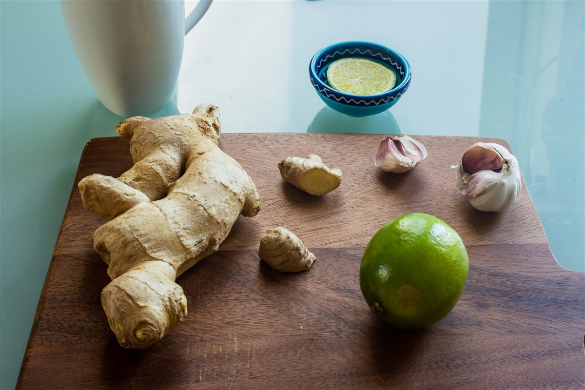 Everyday superfoods &mdash; garlic, lemon, ginger, oats &mdash; laid out on a natural wooden surface
