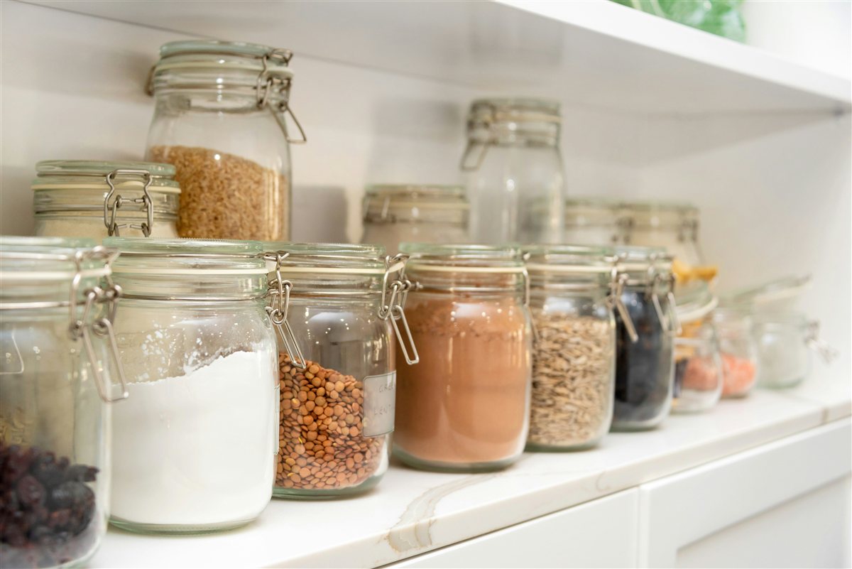 Organised pantry shelves with labelled glass jars